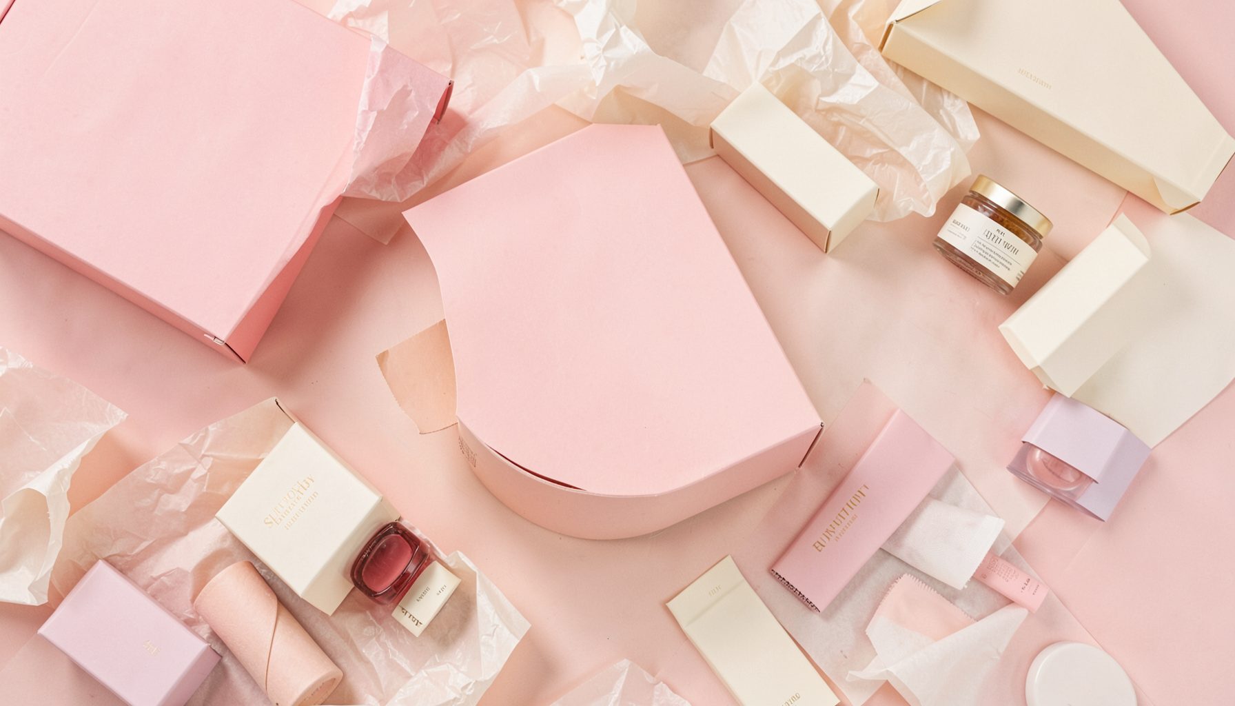 A flat lay of beauty subscription boxes in soft pink and cream tones, surrounded by tissue paper and small product samples, warm and inviting mood.